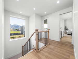 Corridor featuring an upstairs landing, recessed lighting, a mountain view, light wood-style flooring, and plenty of natural light