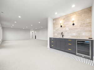Indoor wet bar featuring light colored carpet, recessed lighting, wine cooler, backsplash, and light stone counters