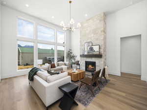Living room with light wood-type flooring, a high ceiling, suspended lighting, and a fireplace