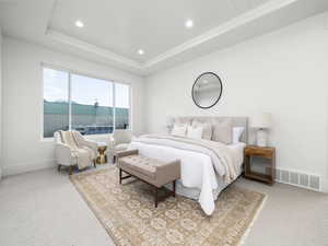 Bedroom with light colored carpet, recessed lighting, and a wood tray ceiling