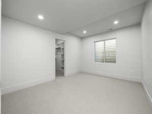 Empty room with light carpet and recessed lighting