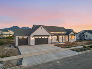 Modern farmhouse featuring a garage, a standing seam roof, concrete driveway, covered porch, and roof with shingles