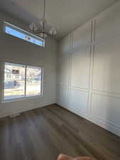 Unfurnished dining area with a decorative wall, dark wood finished floors, plenty of natural light, and a chandelier