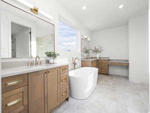 Bathroom featuring two vanities, a freestanding bath, recessed lighting, and a stall shower