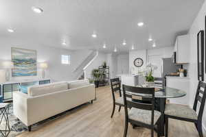 Living room featuring light wood-style floors, recessed lighting, stairs, and a textured ceiling