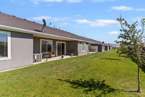 Rear view of property featuring a patio area, a yard, and stucco siding