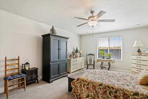 Bedroom with light colored carpet, a textured ceiling, and a ceiling fan