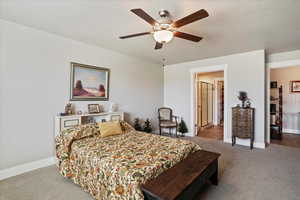 Carpeted bedroom featuring a textured ceiling and ceiling fan