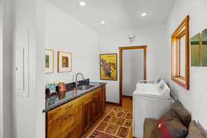 Laundry area with dark wood-type flooring, recessed lighting, washer and dryer, and electric panel