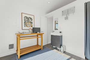 Office area featuring wood finished floors, heating unit, and electric panel