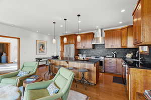Kitchen with a breakfast bar area, brown cabinets, stainless steel appliances, pendant lighting, and tasteful backsplash