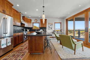 Kitchen featuring plenty of natural light, stainless steel appliances, a kitchen island, dark countertops, and recessed lighting
