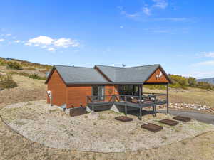 View of front of home featuring a wooden deck and roof with shingles