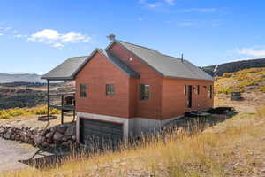 View of property exterior with roof with shingles, an attached garage, and a deck with mountain view