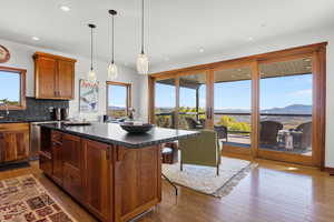 Kitchen featuring a mountain view, dark wood finished floors, decorative backsplash, decorative light fixtures, and a breakfast bar area