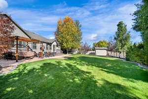 Fully fenced backyard featuring  a patio area, and a storage shed