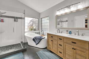 Master en suite Bathroom featuring  vaulted ceiling, a soaking tub, tile  flooring,  double vanity, glass block windows allowing plenty of natural light