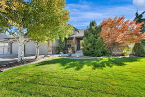 View of front facade featuring a front yard, driveway, 3 car garage and covered porch