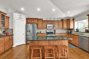 Kitchen with wood cabinets,  appliances with stainless steel finishes, quartz countertop, large island pantry, semi formal dining, great room with sliding door to backyard and plantation shutters