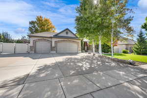 View of front of house with driveway, gated to back yard, 3 car  garage, and covered porch
