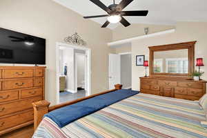 Bedroom featuring vaulted ceiling, a ceiling fan, ensuite bathroom, and wood finished floors