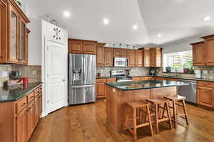 Kitchen with wood cabinets,  appliances with stainless steel finishes, quartz countertop, large island pantry, semi formal dining, great room with sliding door to backyard and plantation shutters