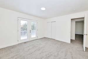 Unfurnished bedroom featuring french doors, access to outside, light colored carpet, and a closet