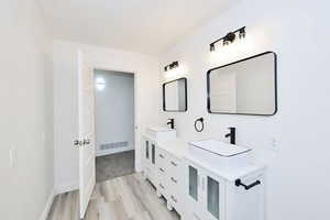 Bathroom featuring double vanity and light wood-style floors