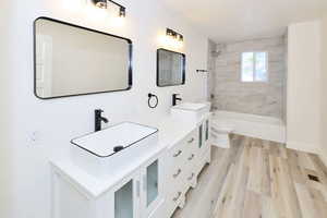 Bathroom featuring shower / washtub combination, double vanity, and light wood-type flooring
