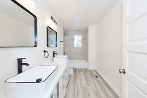 Full bath featuring double vanity, light wood-type flooring, and a stall shower