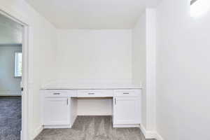 Unfurnished office featuring light colored carpet and built in desk