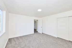 Unfurnished bedroom featuring carpet floors, a closet, and a textured ceiling