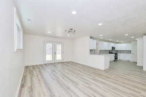 Unfurnished living room featuring light wood-style floors, french doors, recessed lighting, and a textured ceiling