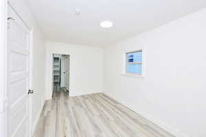 Unfurnished bedroom with light wood-type flooring and a walk in closet