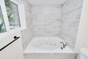 Bathroom with a whirlpool tub and toilet