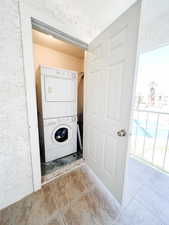 Laundry room featuring stacked washing machine and dryer and light tile patterned flooring
