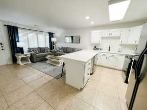 Kitchen featuring a peninsula, white cabinets, appliances with stainless steel finishes, open floor plan, and light countertops