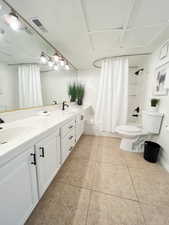 Full bathroom with shower / bathtub combination with curtain, double vanity, and light tile patterned flooring
