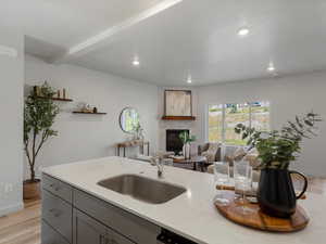 Kitchen featuring gray cabinets, light wood finished floors, a large fireplace, light stone counters, and recessed lighting