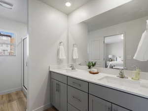 Bathroom featuring light wood-style floors, a stall shower, double vanity, connected bathroom, and recessed lighting