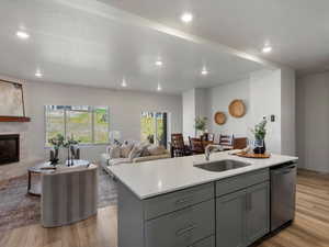 Kitchen featuring gray cabinetry, light wood-type flooring, a fireplace, an island with sink, and a textured ceiling