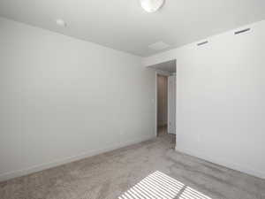 Empty room with light colored carpet and baseboards