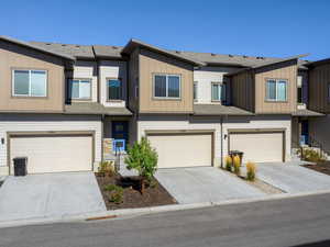 View of front of property with driveway, an attached garage, and a shingled roof