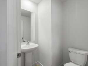 Half bath featuring toilet and baseboards