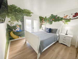 Bedroom with a textured ceiling, light wood finished floors, and french doors