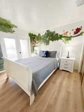 Bedroom with a textured ceiling, light wood-style flooring, and french doors
