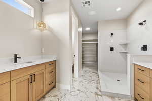 Full bath with vanity, a spacious closet, light marble finish flooring, a marble finish shower, and recessed lighting