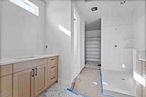 Full bath featuring vanity, a stall shower, and light marble finish flooring