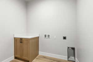 Laundry area with light wood-type flooring, hookup for a washing machine, and hookup for an electric dryer