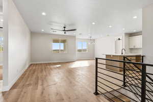 Unfurnished living room featuring a ceiling fan, light wood-style flooring, a chandelier, and recessed lighting
